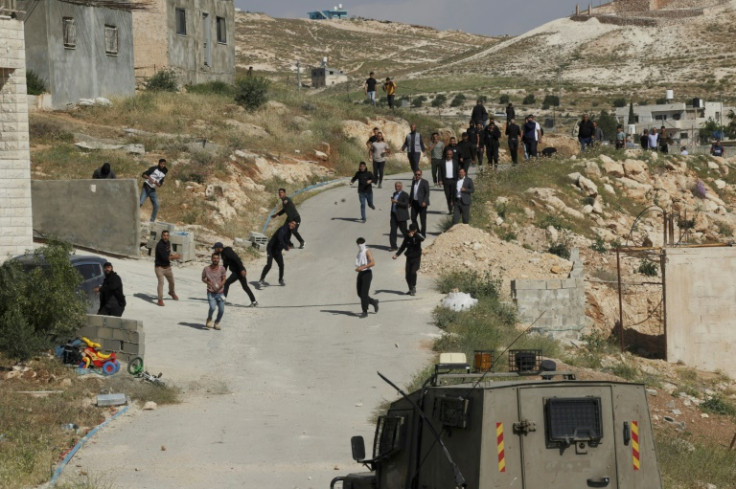 Palestinian protesters throw stones at Israeli troops during confrontations as army bulldozers demolish the school