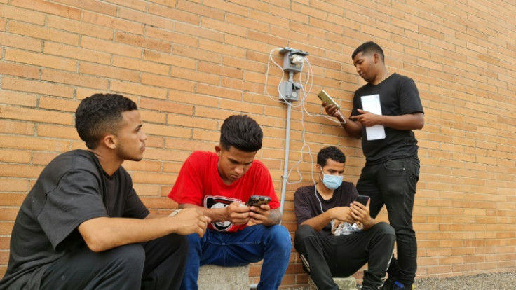 A group of migrants charge their phones outside a Catholic shelter in Brownsville, Texas