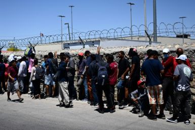 Migrants wait in line to turn themselves in for processing to US Customs and Border Protection border patrol agents in El Paso