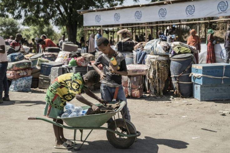 A young boy sells drinks to people in Metema