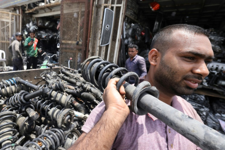 Foreign labourers lugs used car parts at a lot, in the Gulf emirate of Sharjah
