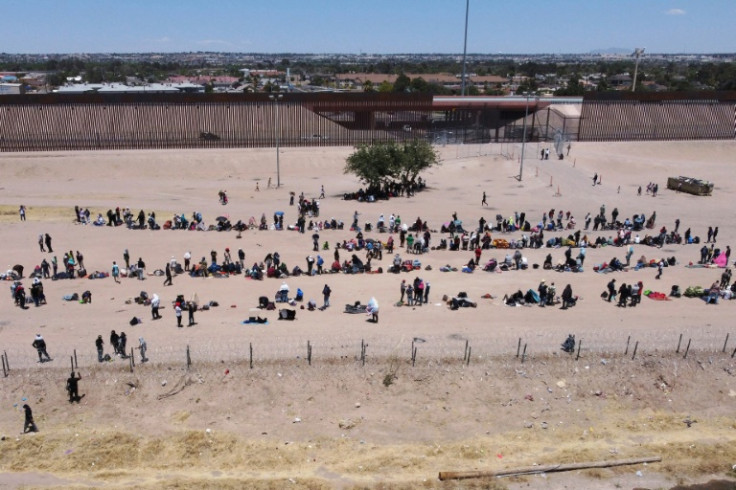 Migrants wait on the banks of the Rio Grande river to be processed by US border officials after crossing from Ciudad Juarez, Mexico