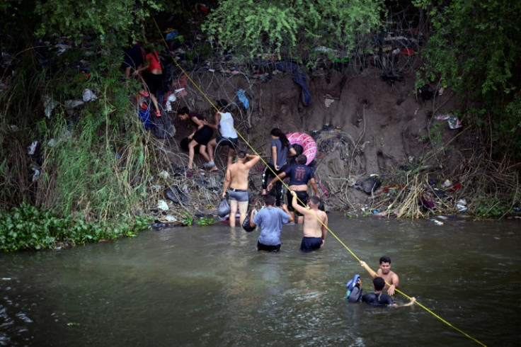 Migrants swim across the Rio Grande river into the United States, as seen from Matamoros, Mexico