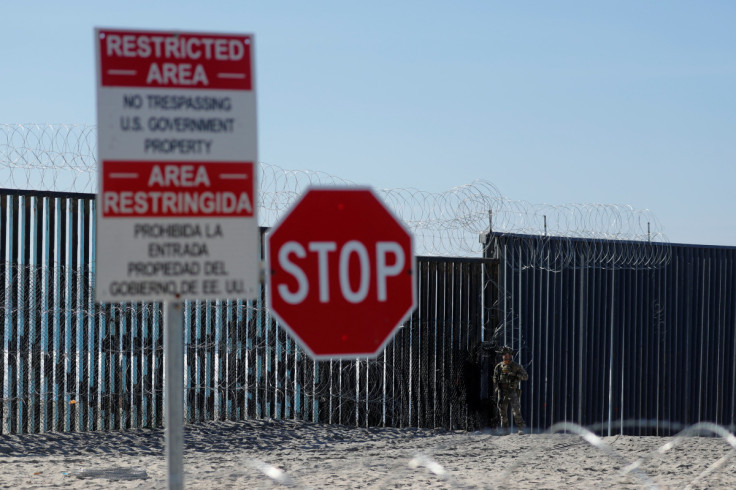 An armed U.S. Customs and Border Patrol agent stands watch at the border fence next the the beach in Tijuana, at the Border State Park in San Diego, California