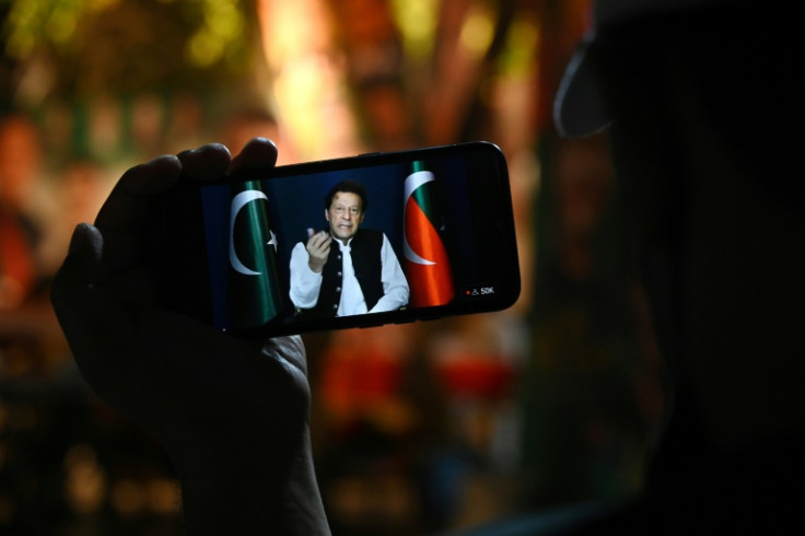 A supporter listens to Pakistani opposition leader Imran Khan's speech on a phone, in Zaman Park in Lahore on May 13, 2023