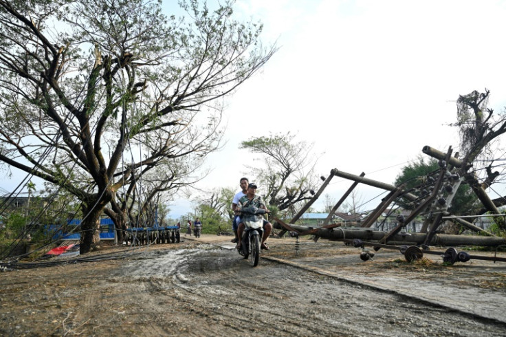 Two men drive past fallen utility poles in Kyauktaw in Myanmar's Rakhine state on May 15, 2023, after Cyclone Mocha crashed ashore on May 14