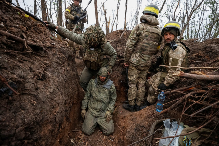 Ukrainian soldiers stay next to a captured Russian army serviceman near the front line city of Bakhmut