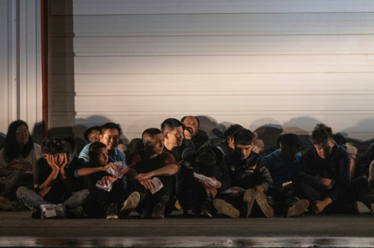 Migrants wait for a bus to take them to a processing center after they turned themselves over to US Border Patrol agents after crossing over from Mexico in Fronton, Texas