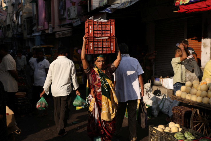 Woman carries boxes of vegetables on her head at a market in Ahmedabad