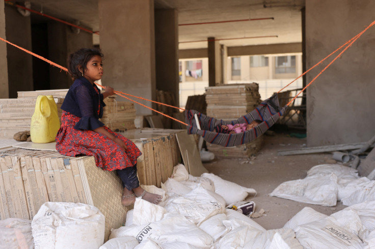 Sonal pushes her younger brother Vaibhav in a makeshift cradle as their mother Heenal works at a construction site in Ahmedabad