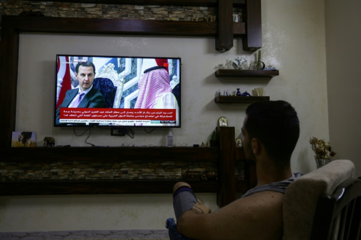 A man in Damascus watches on his television set images of President Bashar al-Assad in Jeddah on the eve of the Arab League Summit