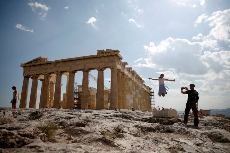 Tourists take a picture in front of the temple of the Parthenon atop the Acropolis in Athens