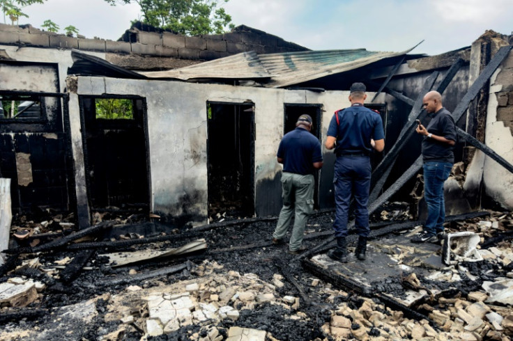 Investigators and government employees inspect the school dormitory where a fire killed at least 19 people in Mahdia, Guyana on May 22, 2023