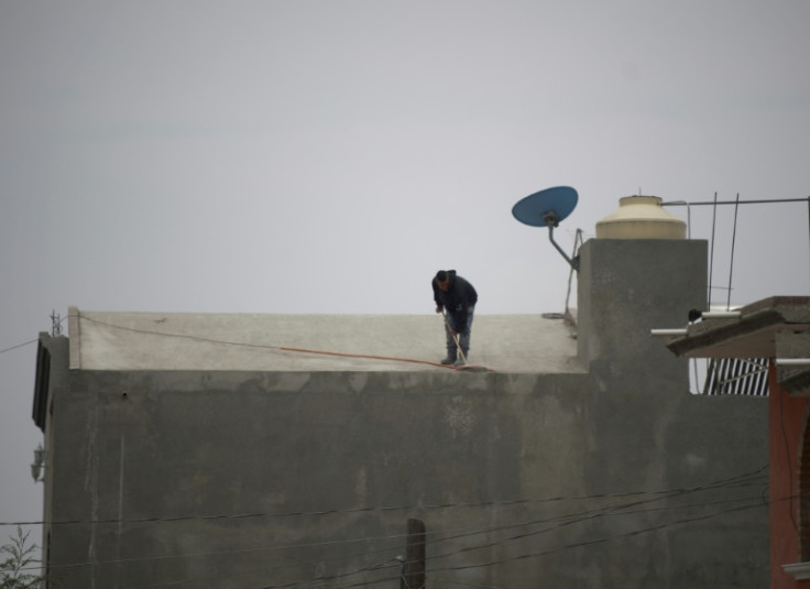 A man sweeps ash from a roof in a town near Mexico's Popocatepetl volcano