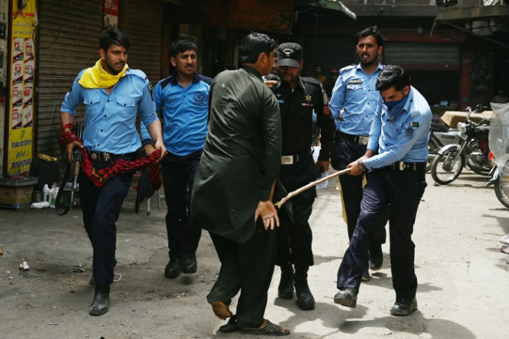 A policeman (R) hits a detained supporter of Pakistan's former prime minister Imran Khan during a  protest against the arrest of their leader