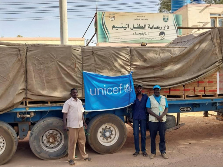 People stand next to a UNICEF flag attached to a truck, in Khartoum