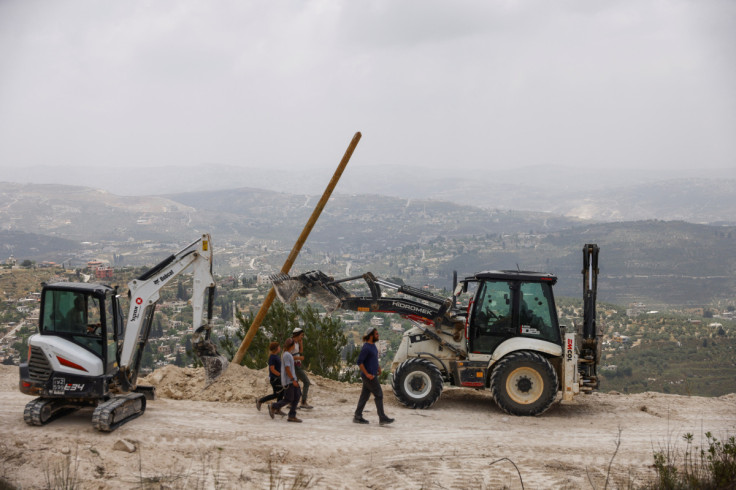 Israeli settlers walk past construction machinery after structures were erected for a new Jewish seminary school, in the settler outpost of Homesh in the Israeli-occupied West Bank
