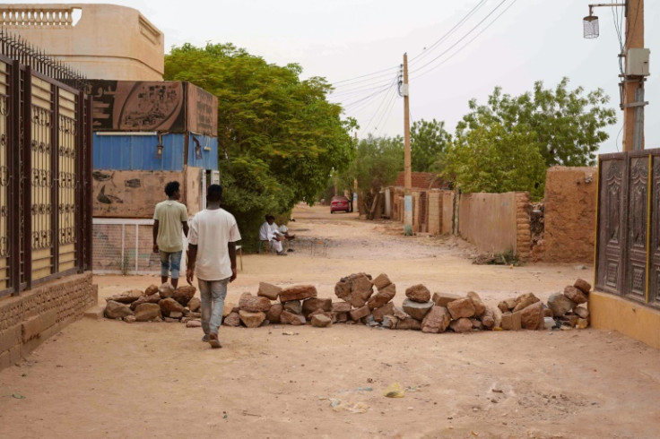 Sudanese walk past a brick roadblock in Omdurman, Khartoum's twin city