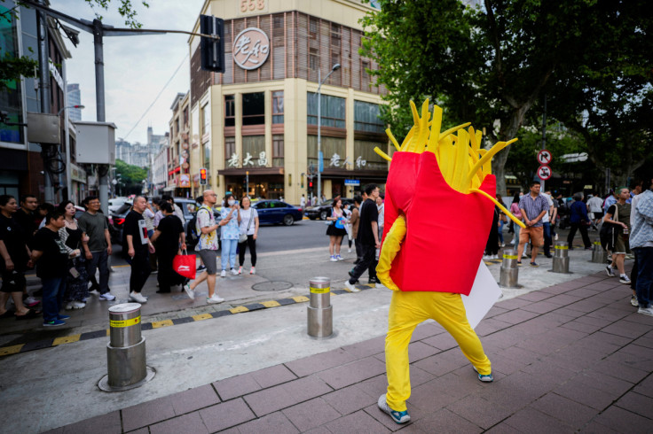 Person dressed as a chips mascot stands in a market on a street in Shanghai