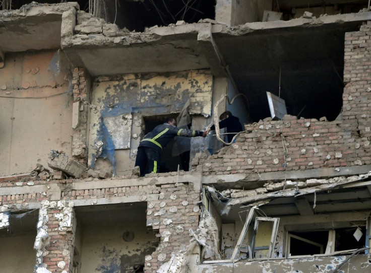 A rescuer evacuates a woman from a multi-storey residential building in Kyiv