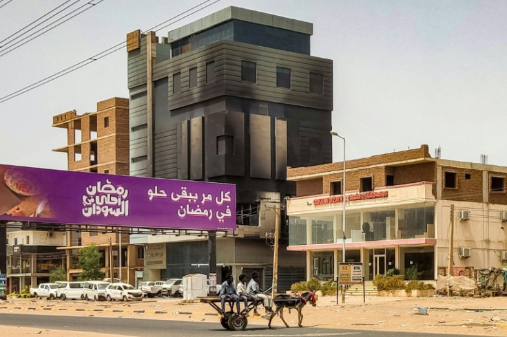 Youths ride in a donkey-drawn cart near the burnt-down headquarters of Sudan's Central Bureau of Statistics, in the south of Khartoum on May 30, 2023