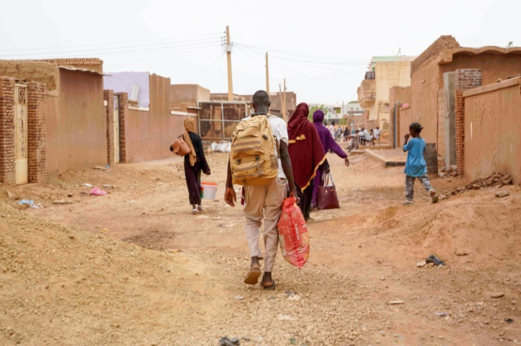 People carrying their belongings walk down on a street in Omdurman, the capital's twin city in war-torn Sudan, on May 29, 2023