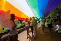 People walk under a giant rainbow flag at the Gay Pride Parade in the Ugandan city of Entebbe in 2015