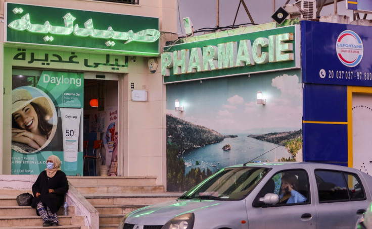 A woman sits near a pharmacy in Tunis