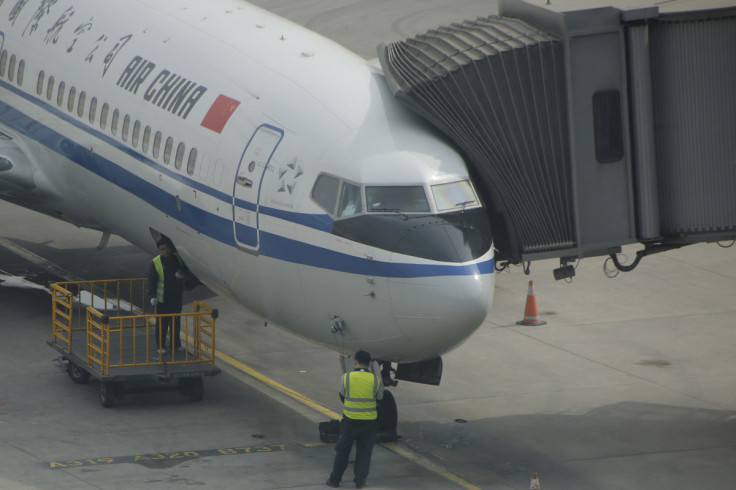 Workers work on a flight of Air China on the tarmac at the Beijing Capital International Airport in Beijing