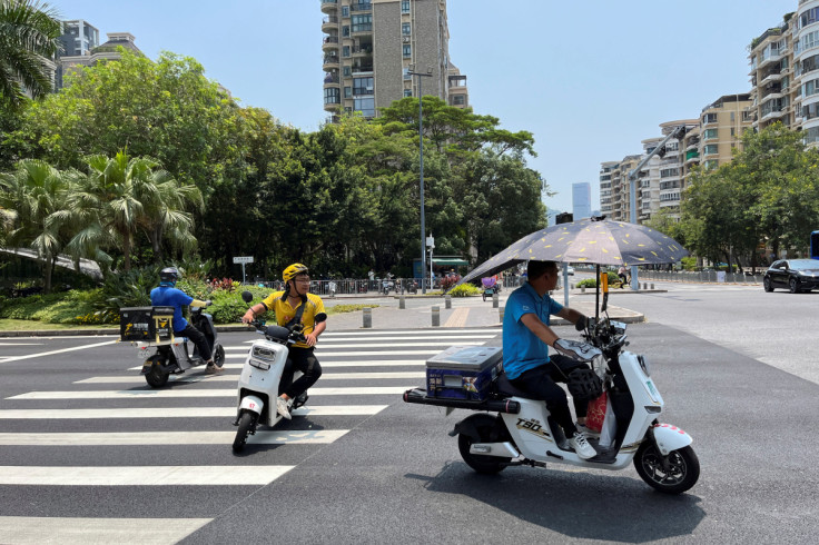 Delivery workers ride scooters in the sun amid a yellow alert for heatwave in Shenzhen