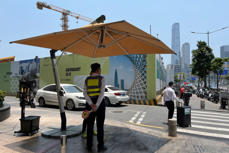 Security personnel stand in shade amid a yellow alert for heatwave in Shenzhen