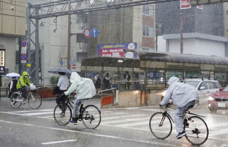 People riding bicycles make their way in the heavy rain in Kochi