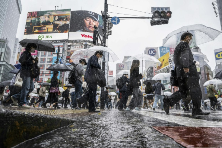 People use their umbrellas to shelter from the rain as they walk through Tokyo's Shibuya district