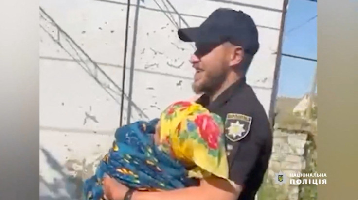 A woman is being carried as police officers, together with rescuers of the State Emergency Service, conduct patrols and help citizens evacuate to safe places, following floods, in Kherson region