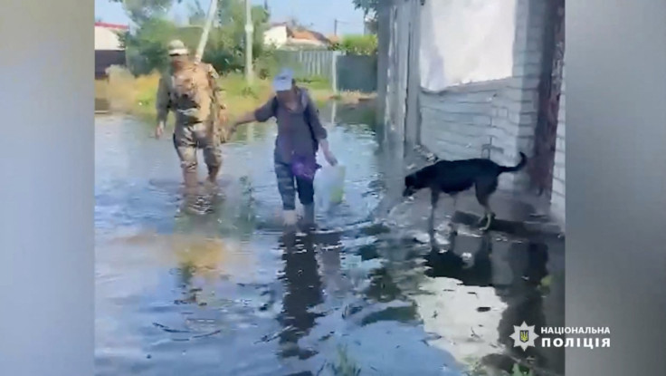 A person wades through floodwaters as police officers, together with rescuers of the State Emergency Service, conduct patrols and help citizens evacuate to safe places, in Kherson region