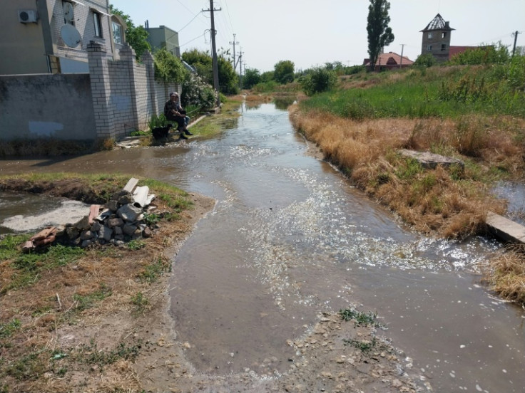 Flood water pours down a road on the outskirts of Kherson