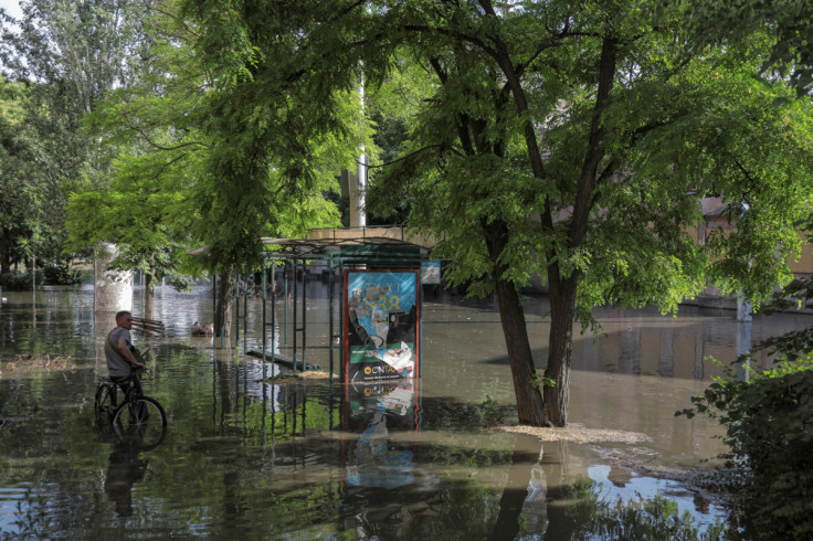 Local resident stands next to a public transport stop on a flooded street after the Nova Kakhovka dam breached, in Kherson