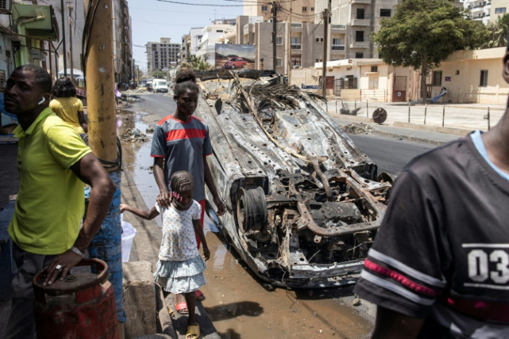 Destruction: People walk past a burnt-out car in Dakar
