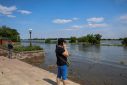 Local resident speaks on her mobile phone on an embankment of the Dnipro river which flooded after the Nova Kakhovka dam breached, in Kherson