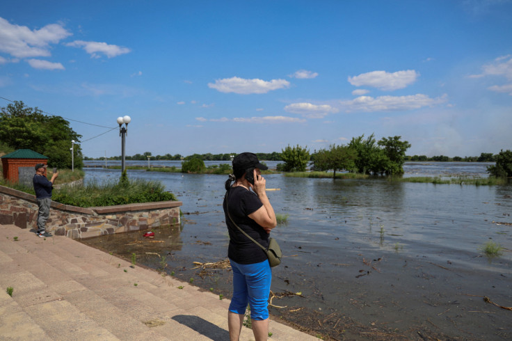 Local resident speaks on her mobile phone on an embankment of the Dnipro river which flooded after the Nova Kakhovka dam breached, in Kherson
