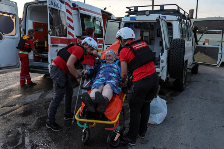 Red Cross volunteers help an elderly woman evacuated from a flooded area after the Nova Kakhovka dam breached, in Kherson
