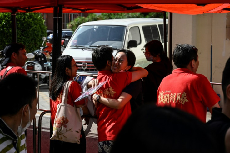 A student (C) hugs her teacher before entering the school on the first day of China's national college entrance examination, known as the gaokao, in Beijing on June 7, 2023.