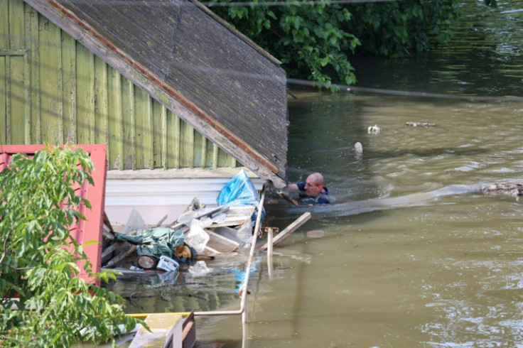 A man swims by a house in a flooded area in Kherson