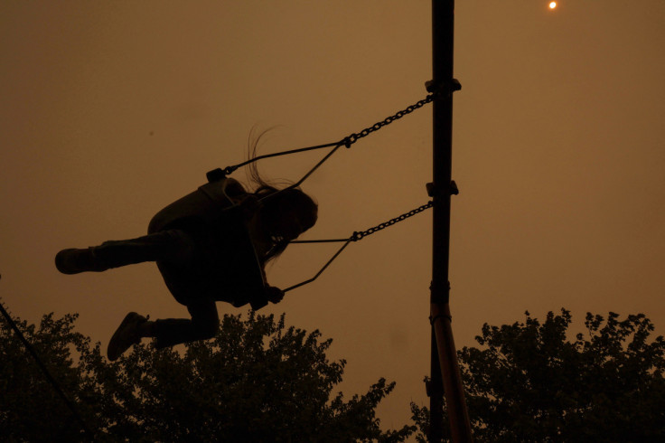 A girl on a swing is seen in silhouette as haze and smoke from the Canadian wildfires shroud the sky at Barretto Point Park in the Bronx borough of New York City