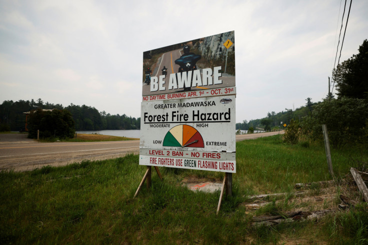 A fire hazard sign sits beside a highway near a forest fire that has been burning since Sunday on the shore of Centennial Lake in the Township of Greater Madawaska