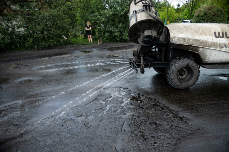 A vehicle sprays water to dampen down coal dust outside Iwona Wozniewska's home in Gdansk, Poland