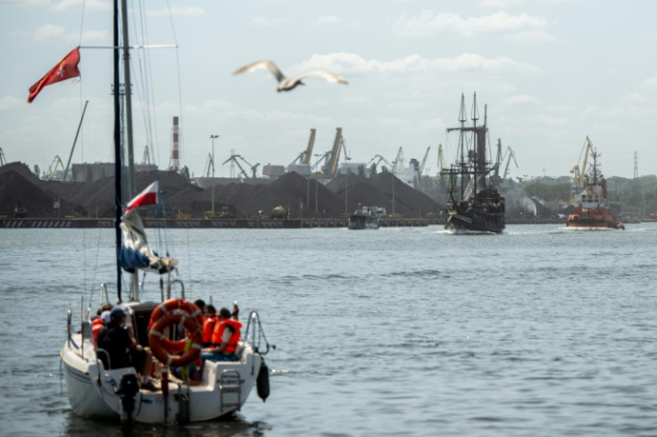 Tourist boats pass through the port of Gdansk, Poland with its huge piles of coal