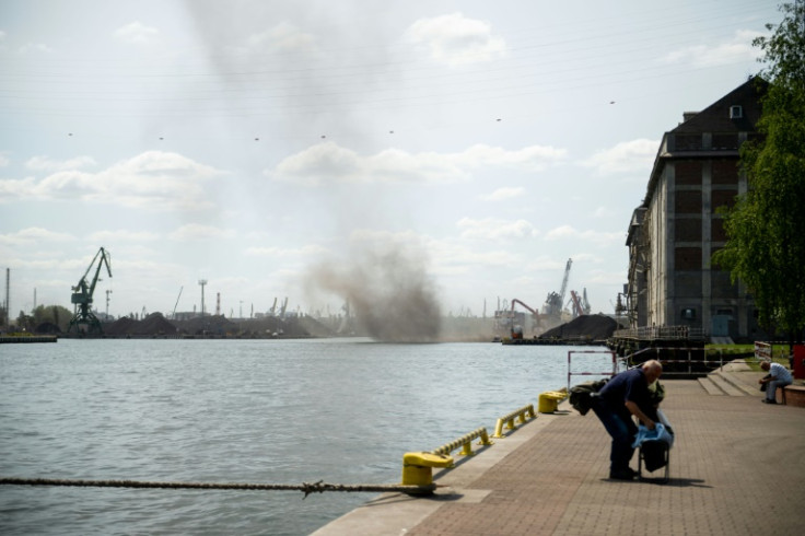 A man packs up to leave as a large cloud of coal dust swirls over the port of Gdansk, Poland