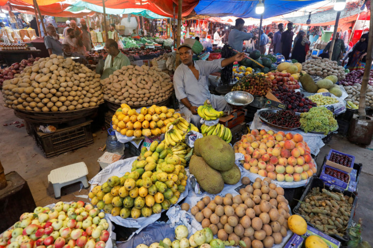 Vendor speaks with a customer while selling fruits at a market in Karachi