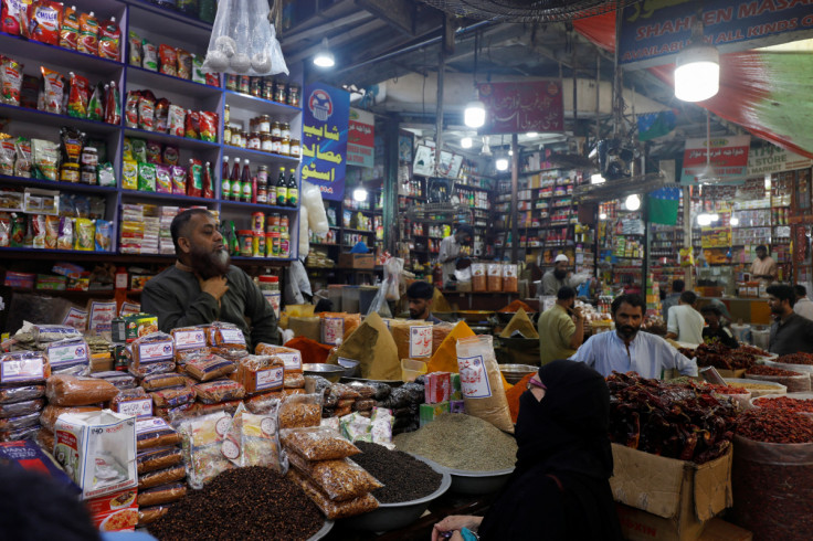 A customer speaks with a shopkeeper selling grocery items at a market in Karachi